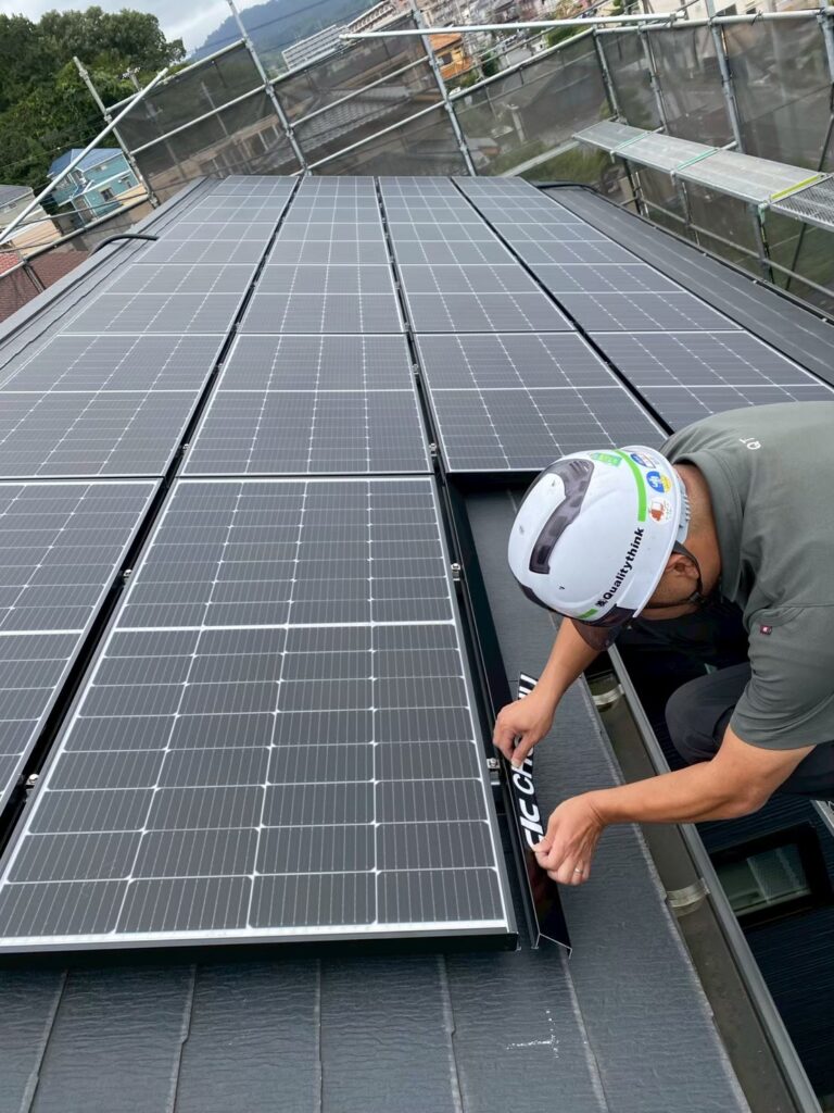 太陽光パネルの下部にエンドカバーを取り付け、仕上げ作業を行う職人